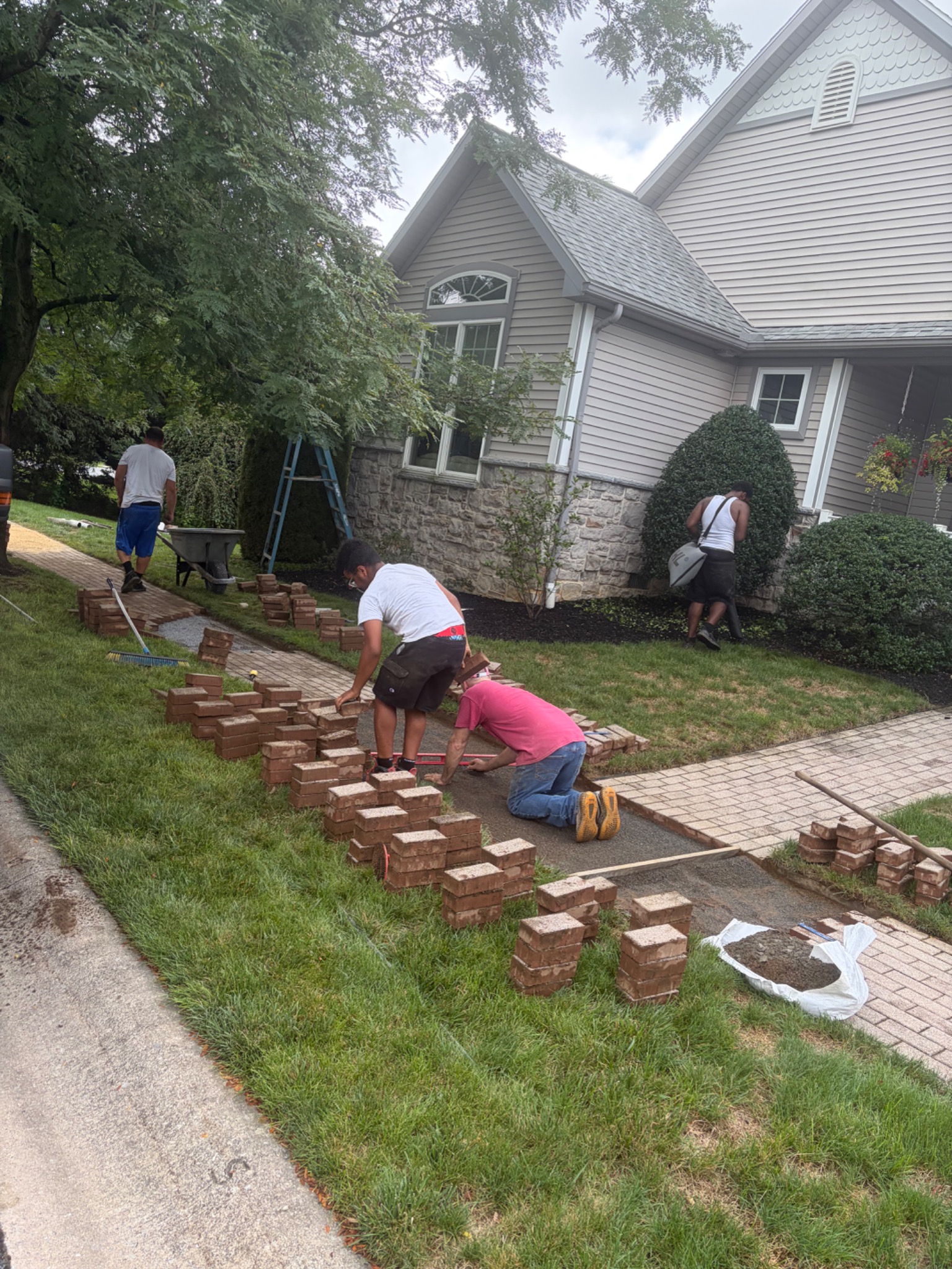 Crew lifting pavers and leveling a walkway base