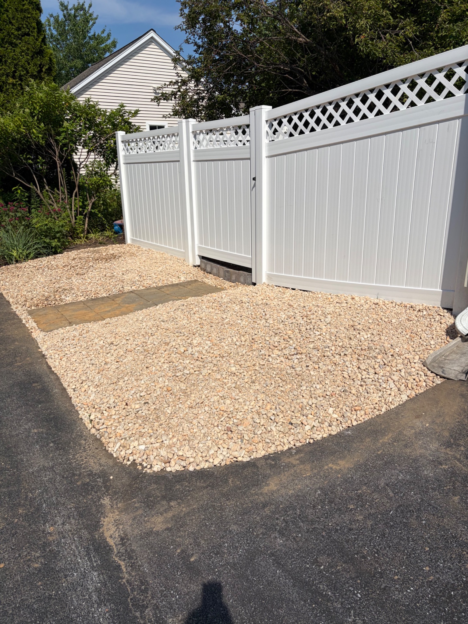After: a clean decorative stone bed and paver access at the same gate